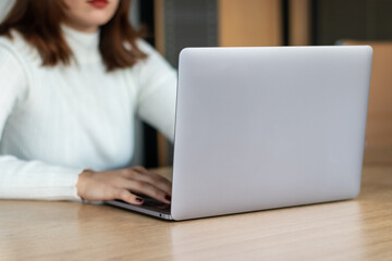 woman in white sweater working with laptop in office