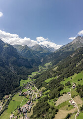 Naklejka na ściany i meble Aerial drone shot of Helligenblutt village in with view of Grossglockner mountain in Austria