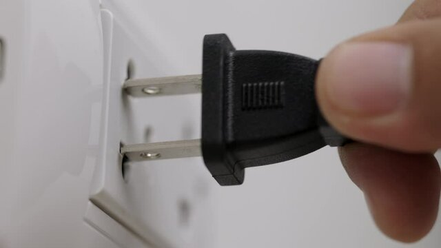 Hand holding Electric plug put on multiple socket. Electrical equipment, electrical wires and power strips in the house. Earth Hour saving electrical energy.