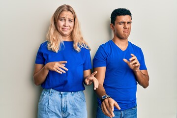 Young interracial couple wearing casual clothes disgusted expression, displeased and fearful doing disgust face because aversion reaction.