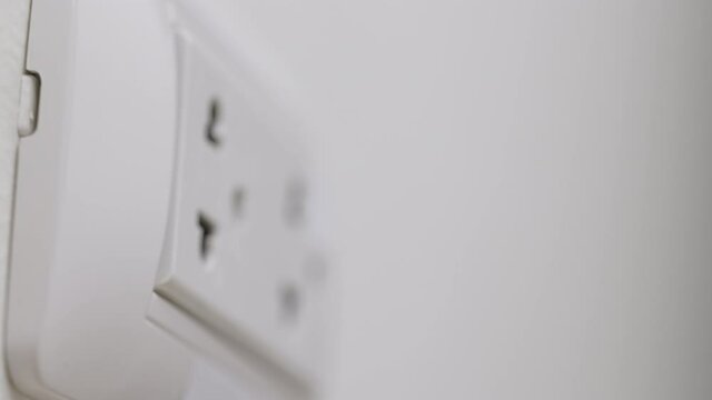 Close up male hand remove the Electric adapter smartphone or laptop plug. Electrical wires and power strips in the house