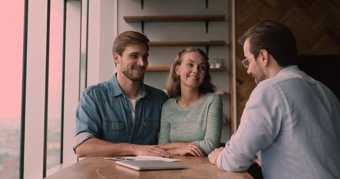 Smiling bonding caucasian family couple taking professional consultation from realtor, making decision of buying own apartment, signing agreement at office meeting, getting keys from own dwelling.