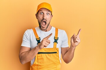 Young handsome man wearing handyman uniform pointing to the side celebrating crazy and amazed for...
