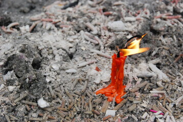Red candle burning over ashes