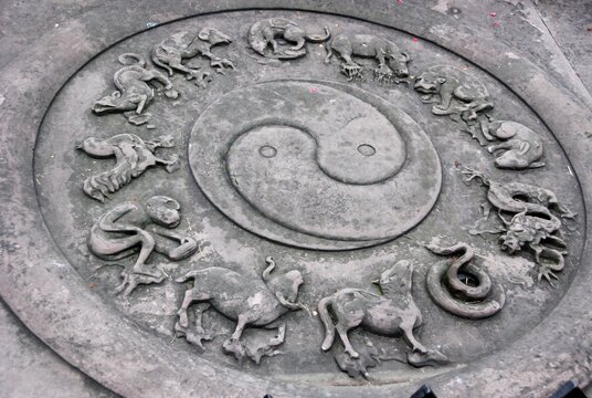 yin yang and chinese horoscope embossed on an ancient stone