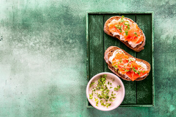 Toasted bread with ricotta (cream cheese), smoked salmon and micro greens. Health care, super food concept. Stone background. Top view. Copy space.
