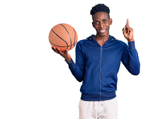 Young african american man holding basketball ball surprised with an idea or question pointing finger with happy face, number one