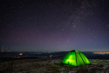 Night at the top of the mountain in a tent in winter against the background of the starry sky