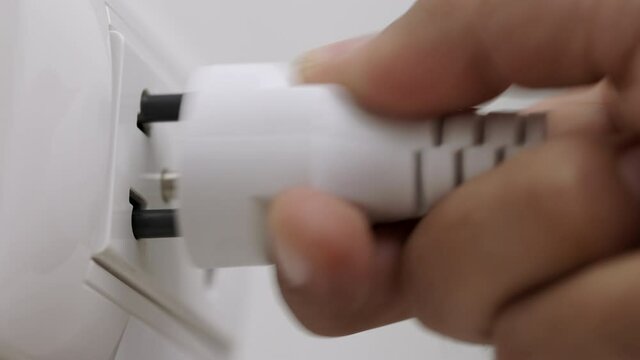 Hand holding Electric plug put on multiple socket. Electrical equipment, electrical wires and power strips in the house. Earth Hour saving electrical energy.