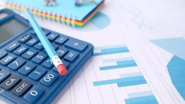 Close up of blue calculator and financial chart on table.