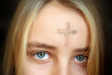Girl with cross made from ash on forehead. Ash wednesday concept.