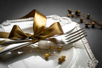Romantic tabble setting with ribbon, plates, cutlery on black background. Empty plate. Mockup...
