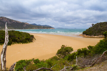 Australian landscape in November with sandy beach, blue sky, mountains and sea.