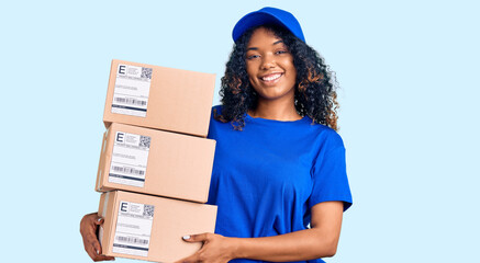 Young african american woman holding delivery package looking positive and happy standing and...