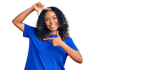 Young african american woman wearing casual clothes smiling making frame with hands and fingers...