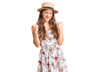 Obraz na płótnie Canvas Beautiful caucasian young woman wearing summer hat excited for success with arms raised and eyes closed celebrating victory smiling. winner concept.