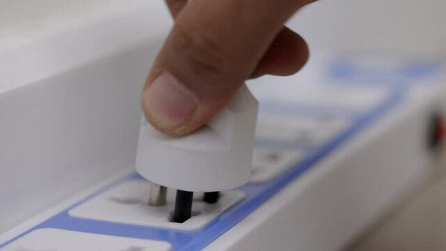 Hand holding Electric plug put on multiple socket. Electrical equipment, electrical wires and power strips in the house. Earth Hour saving electrical energy.