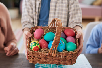 Close-up of child holding basket with colored Easter eggs