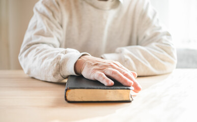 senior man praying, reading  an old Bible in his hands.