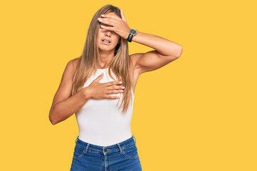 Young blonde woman wearing casual style with sleeveless shirt touching forehead for illness and fever, flu and cold, virus sick