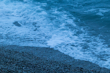 beautiful, blue sea with waves, foam, beach, rocks in the evening in good weather