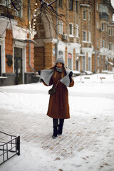 the girl closed her eyes and holds a scarf in her hands in winter