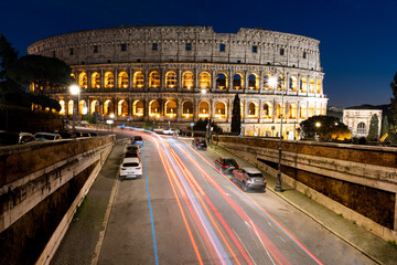 Naklejka premium lunga esposizione notturna del colosseo, con scie di luce delle auto 