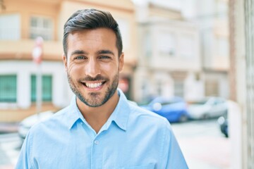 Young hispanic man smiling happy standing at street of city.