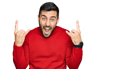 Fototapeta premium Young hispanic man wearing casual clothes shouting with crazy expression doing rock symbol with hands up. music star. heavy music concept.