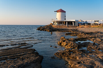Fototapeta na wymiar Restored windmill at a a beach of Skyros island in Greece at sunset