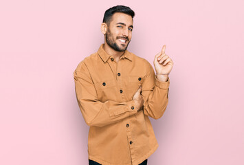 Young hispanic man wearing casual clothes with a big smile on face, pointing with hand and finger...