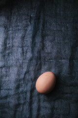 One egg on dark fabric background. Easter, spring or eco food concept. Top View