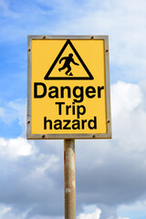 Danger trip hazard yellow sign with blue sky background
