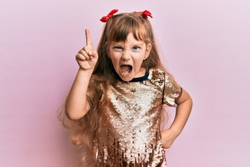 Little caucasian girl kid wearing festive sequins dress pointing finger up with successful idea. exited and happy. number one.