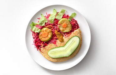 Oatmeal pancake and salad on a white plate in the form of a cheerful smiley. healthy breakfast.
