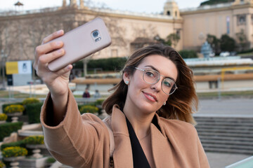 Young blonde woman with glasses takes selfie in the city