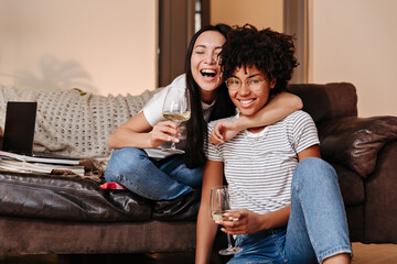 In relaxed atmosphere two beautiful young girls with bright hairstyles and stylish make-up drink...