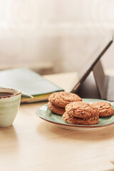 Workplace, homeoffice with tablet, tablet pc or iPad, notebook, cup of coffee  and cookies  on the desk. Online working, learning concept. Selective focus, stock photo