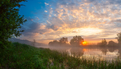 Summer landscape with river and foggy sunrise