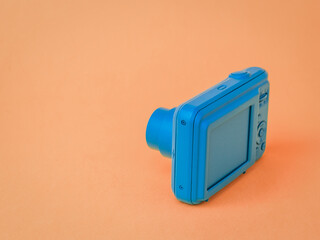 A blue camera with a retractable lens on a brown background.