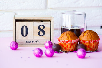Wooden calendar and a cup of coffee with sweets on the table. Celebration of International Women's Day on March 8