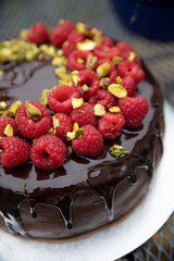 Rich chocolate layer cake with raspberries and a melted chocolate drip on top 