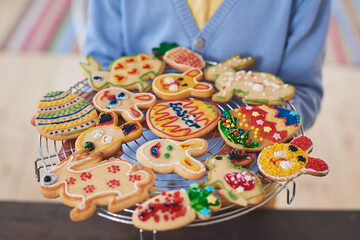 Close-up of woman holding tray with decorated baked cookies preparing for Easter