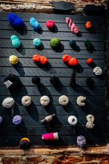knitting threads are hung on nails to the black wall, as an addition to the interior of the store or home