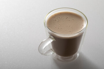 Cappuccino with chocolate in a glass cup on a white background.