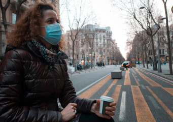 woman with a mask having a takeaway coffee in a street in Barcelona. Many cities have established as an anti-covid measure the prohibition of eating or drinking inside restaurants and bars
