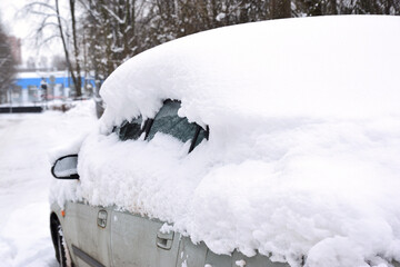 A car covered with a thick layer of snow on a city street