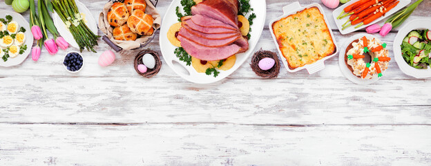 Traditional Easter ham dinner. Overhead view top border on a white wood banner background with copy...