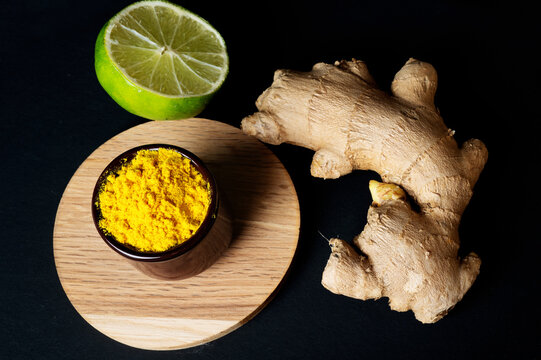  raw ginger and laim with curcuma seasoning around black background.  healthy and food concept. close up