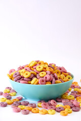 Vertical shot of multicolored fruity cereals in a blue bowl isolated on white background